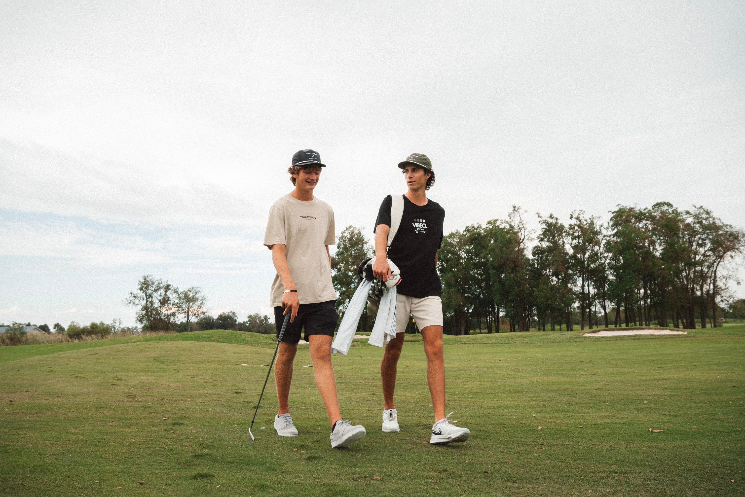 Two Guys Walking A Golf Course Wearing VIBEOSTUDIOS Organic/Recycled Clothing 